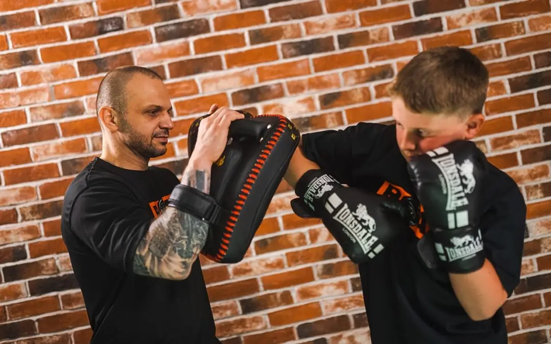 Coach holds pad while young boxer wearing Lonsdale gloves practices strikes at Roar Martial Arts