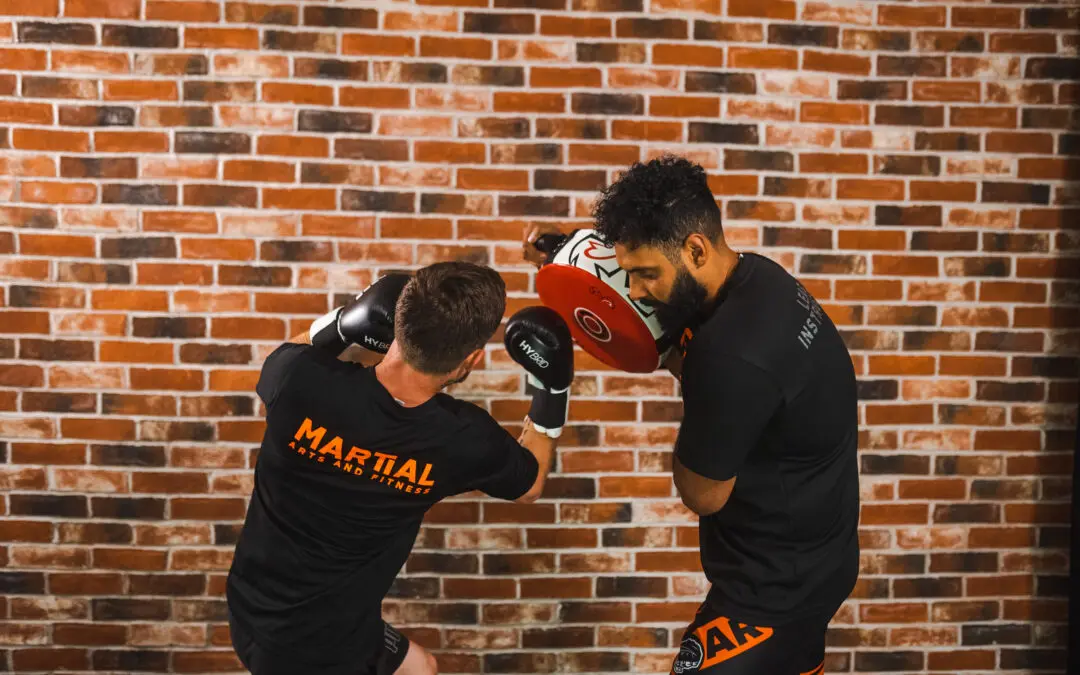 Trainee strikes focus pad held by instructor during martial arts and fitness session at Roar.