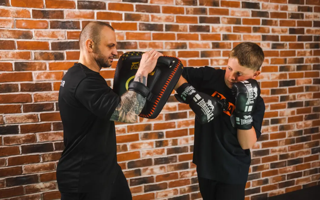 Roar Martial Arts coach trains a young boy with focus pad boxing drills