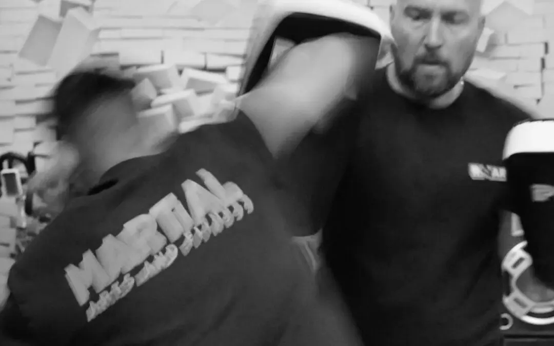 Athlete throws powerful kick at pad while coach supervises training session at Roar Martial Arts