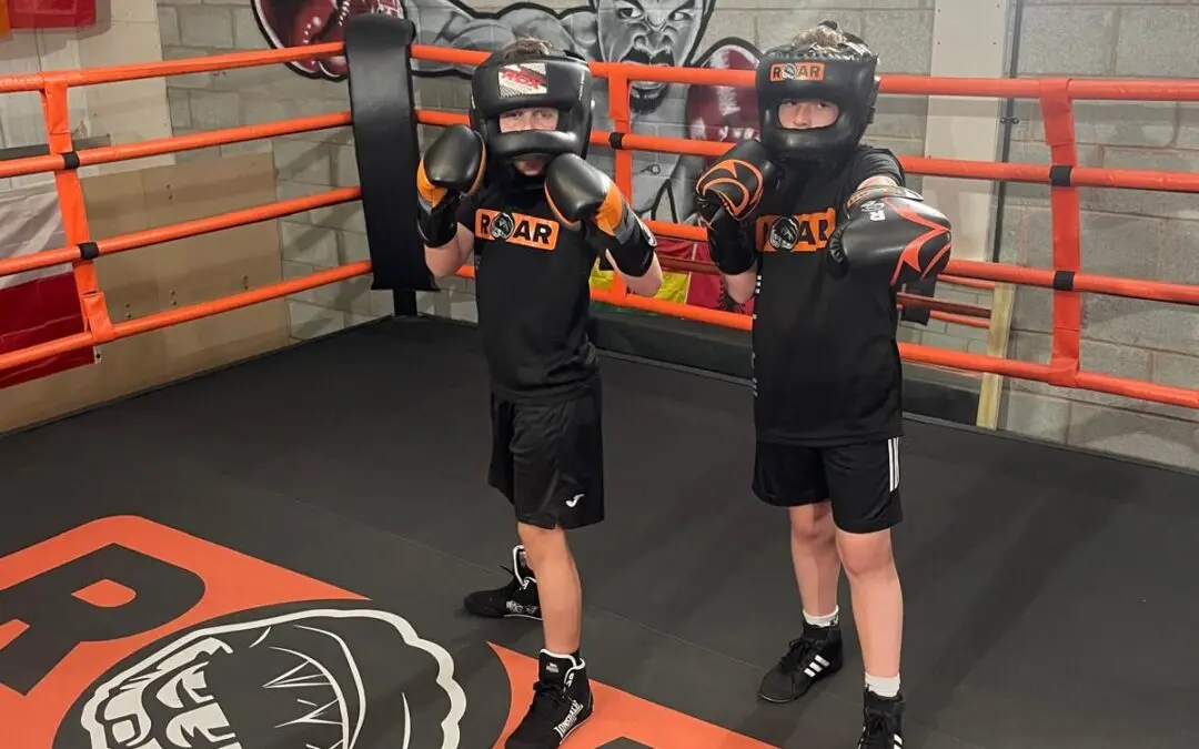Two young boxers in headgear pose ready inside Roar Martial Arts ring before sparring practice