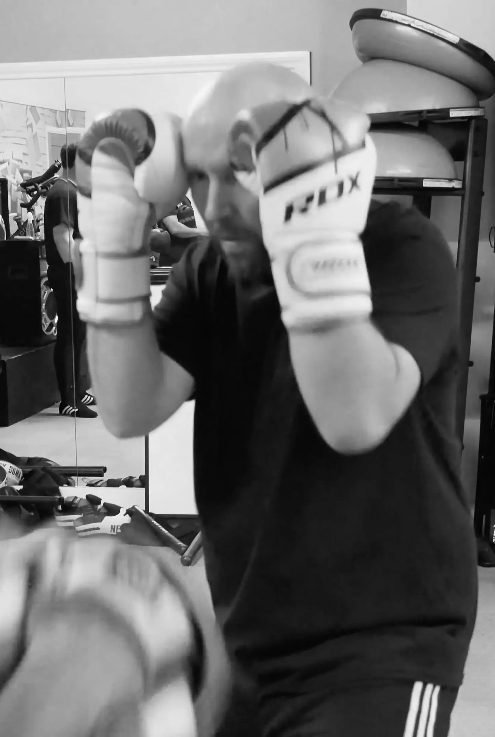 Black-and-white photo of a boxer in gloves holding a defensive fighting stance