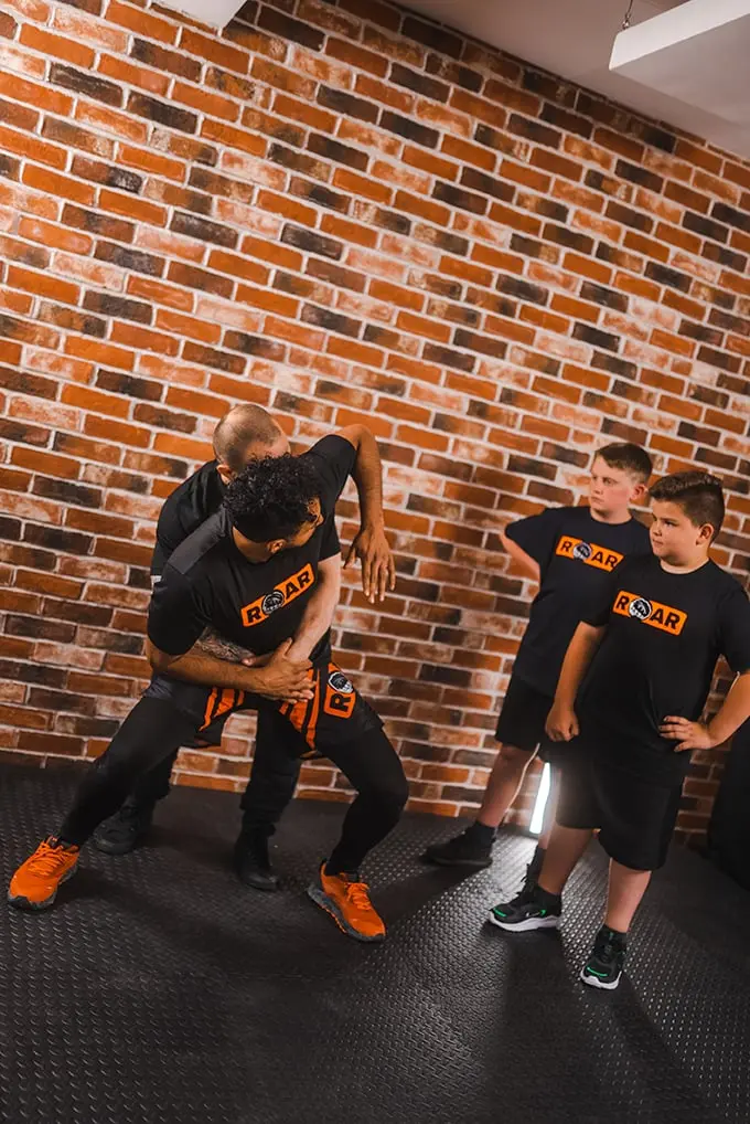 Roar Martial Arts instructor demonstrating self-defence grappling technique to young students