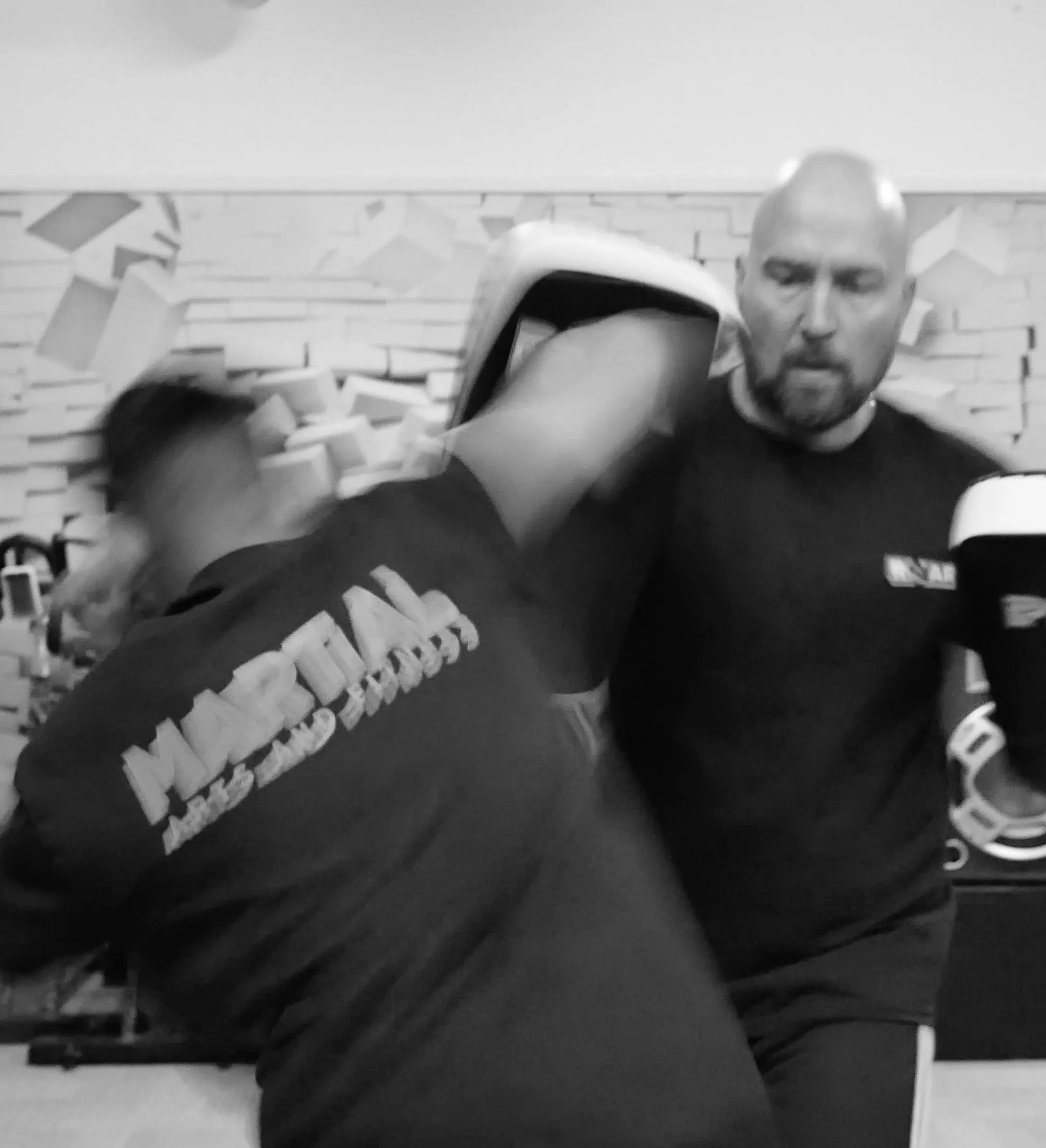 Black-and-white photo of a Roar Martial Arts student striking a focus pad with speed